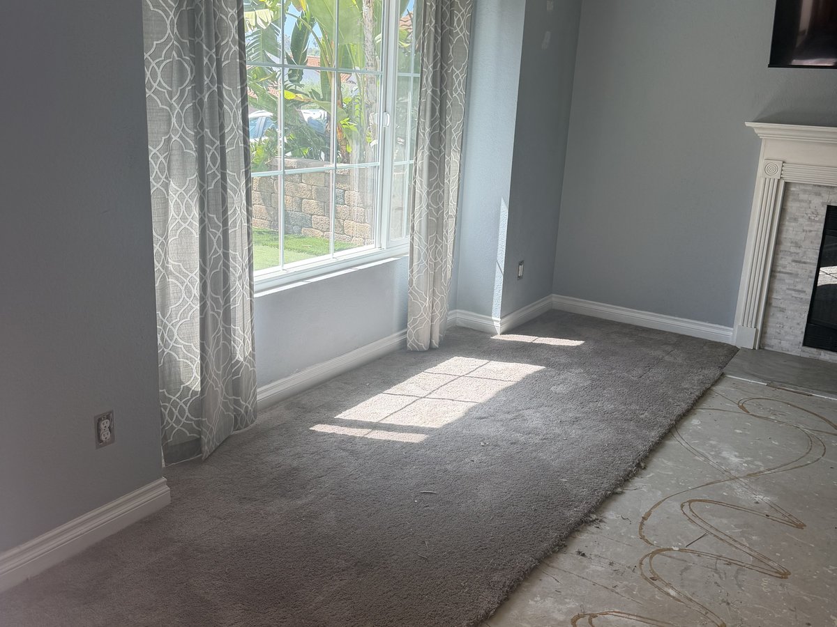 The same living room cleared down to the bare subfloor, ready for new flooring, after