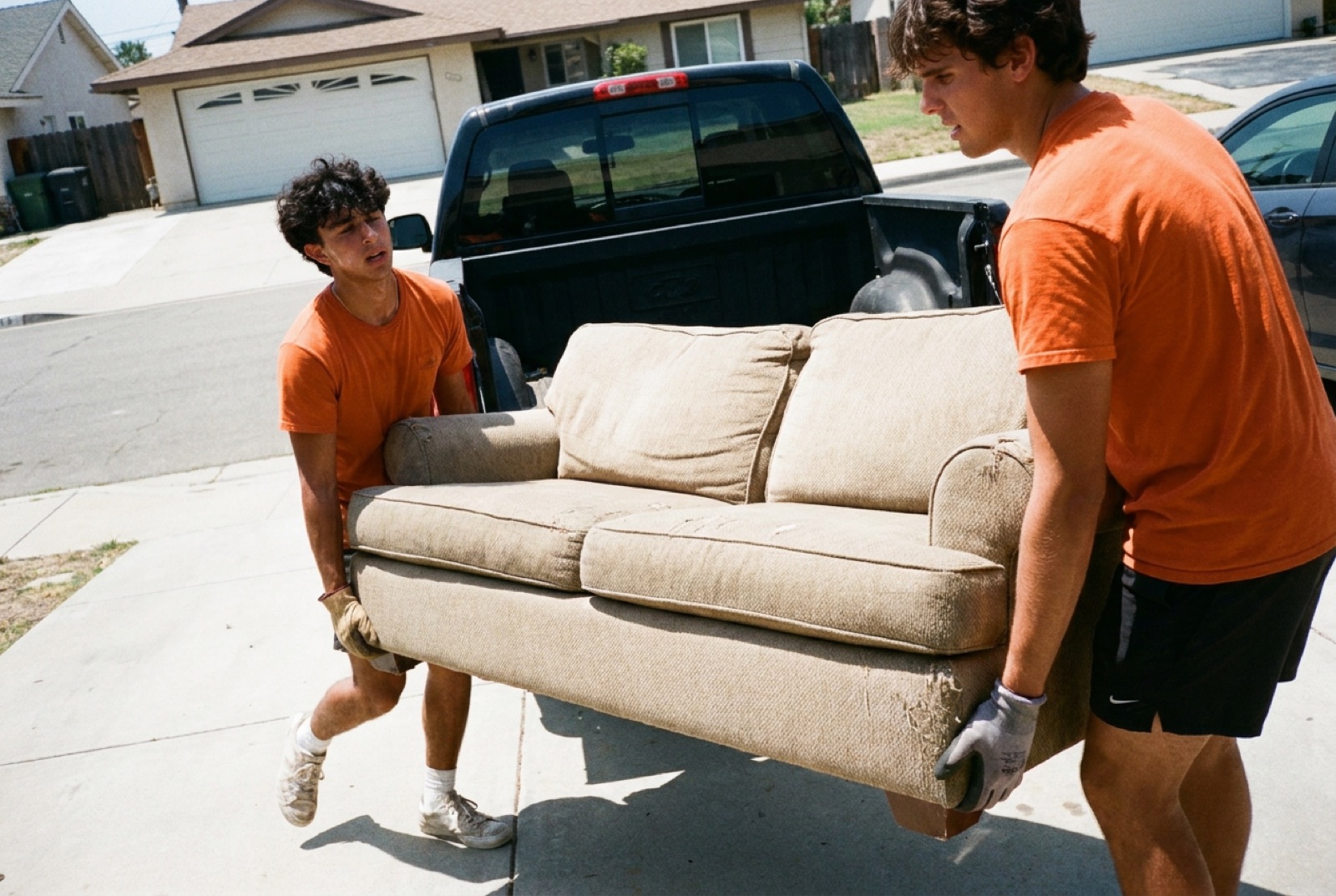 The Haul Boys crew loading an old couch into their pickup truck in a San Diego driveway