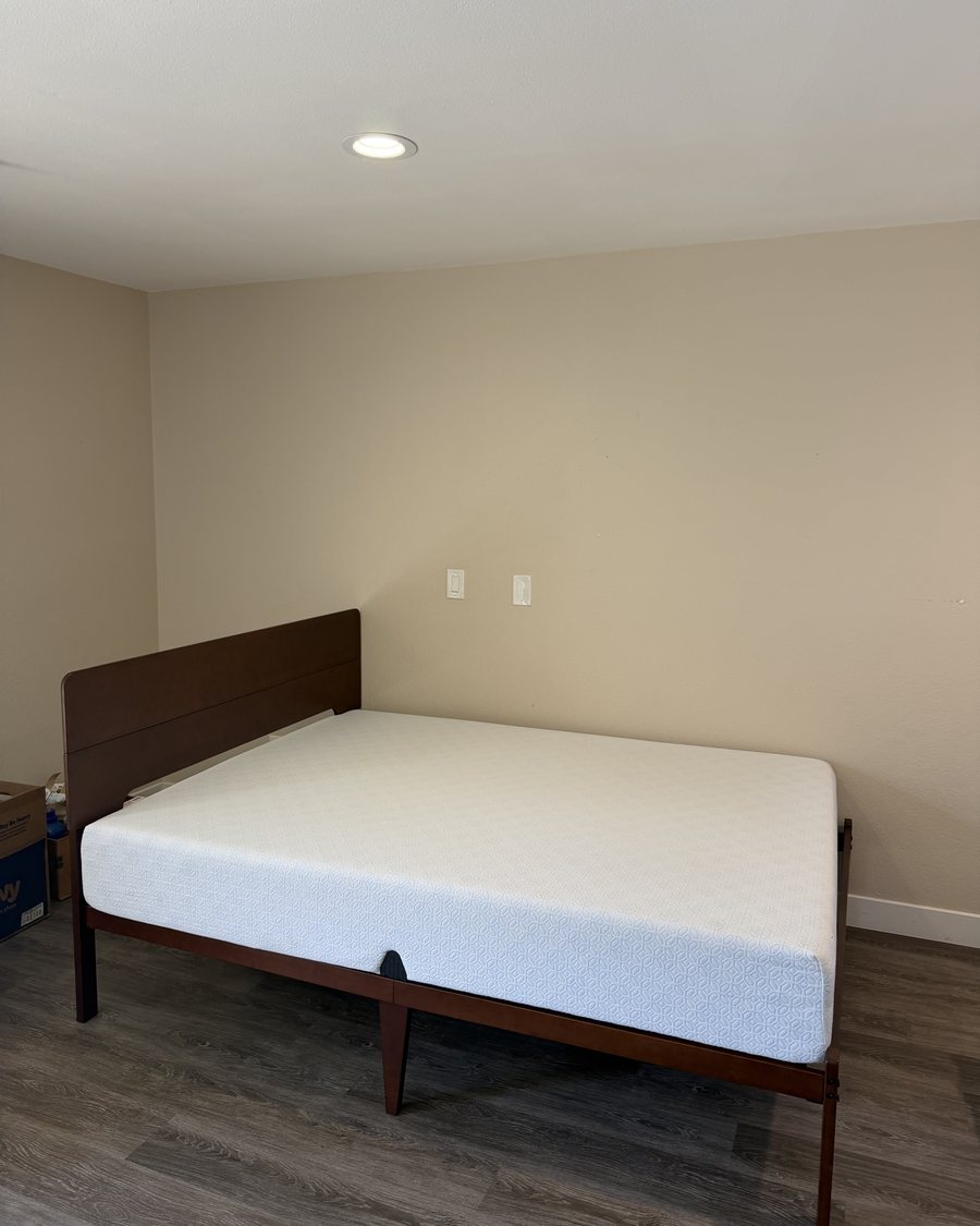 Queen bed frame and mattress assembled and set against the wall of a customer's bedroom