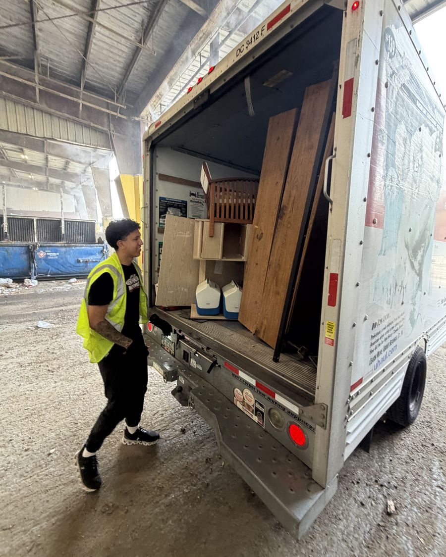 Crew member in a safety vest unloading wood and furniture at the recycling center