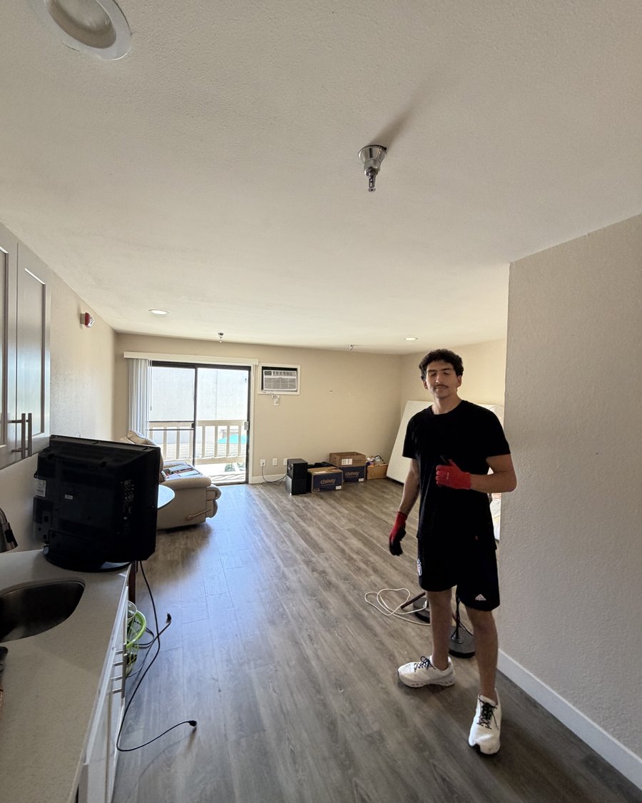 Crew member in a retirement community apartment with the resident's TV, recliner and boxes moved into the new unit